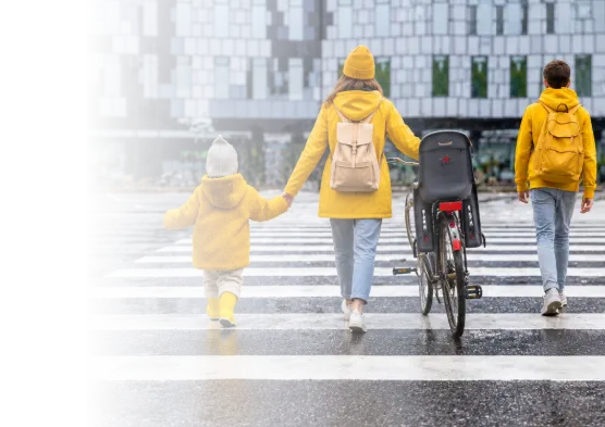 Trois personnes portant des vêtements jaunes traversent un passage piéton avec un vélo dans un environnement urbain.

Description générée par IA