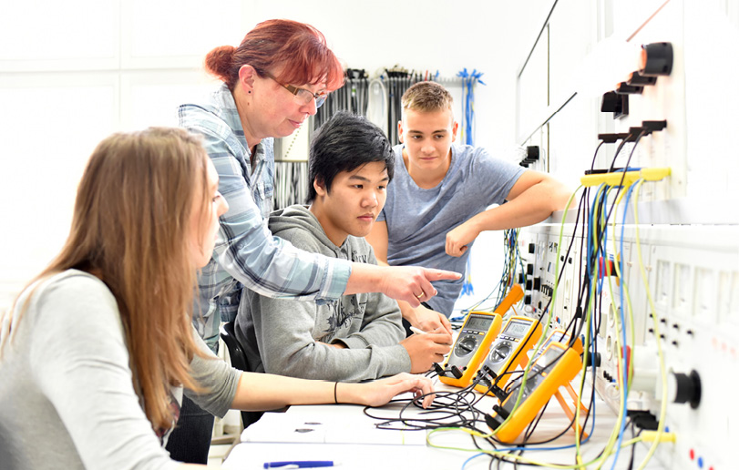 Quatre personnes assises à une table manipulent des appareils de mesure électroniques dans un environnement technique lumineux.

Description générée par IA
